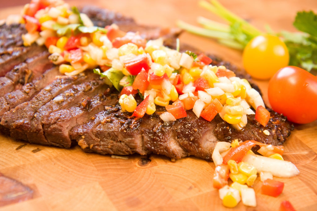 A whole flank steak served with corn salsa